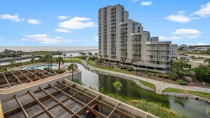 A high-rise hotel with multiple balconies, a pool, and a landscaped area with a water feature. - Recently Renovated Oceanfront Condo, Private Resort +Free Attraction Tickets! (Myrtle Beach)