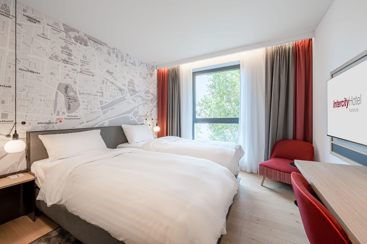 A hotel room with two beds, a desk, and a chair.