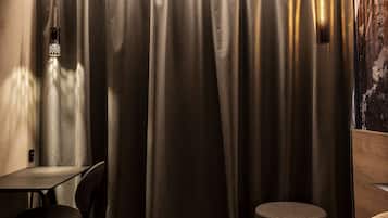 Habitación de hotel con cama, una mesita redonda, una silla y una lámpara de pared.