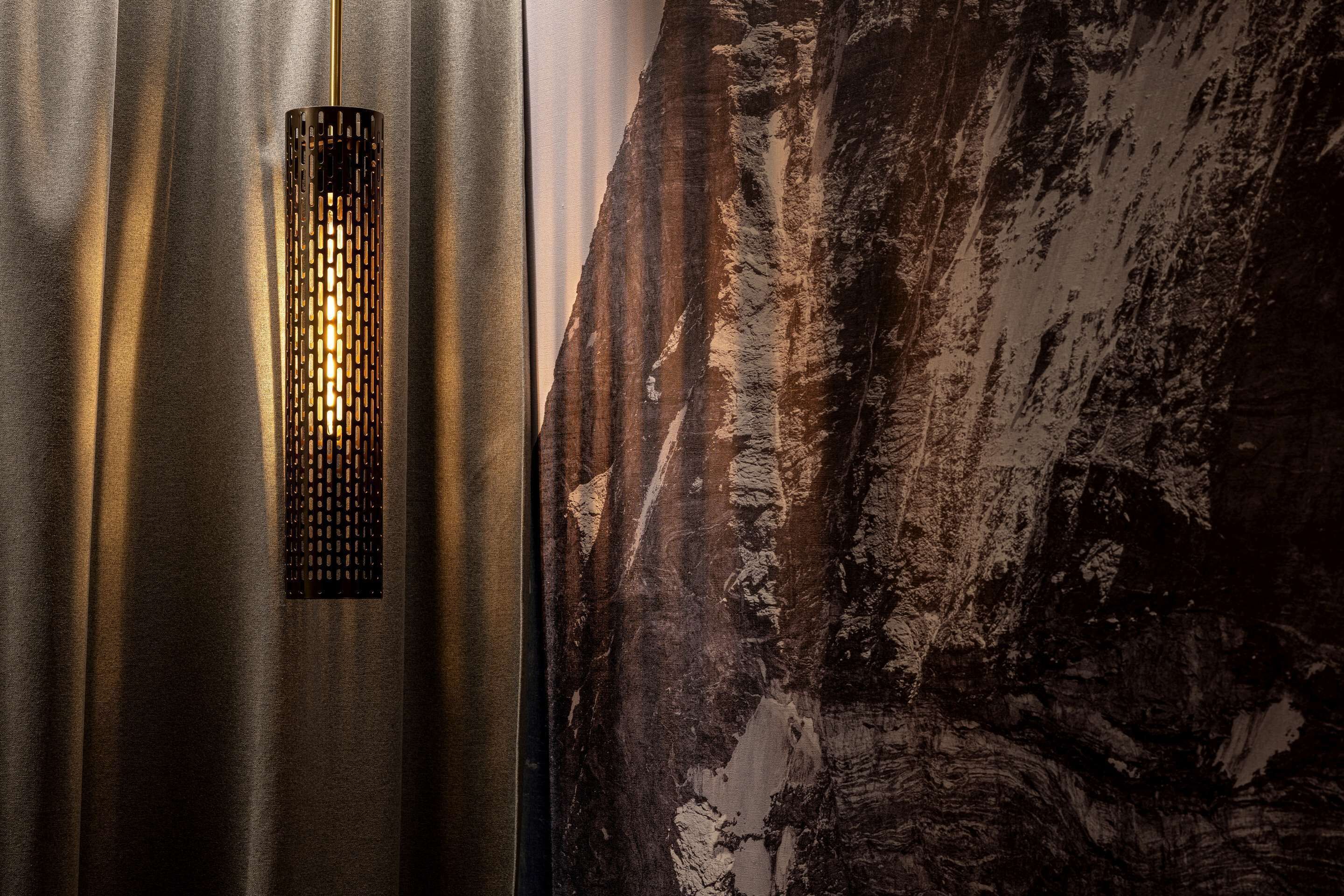 A metallic wall with a textured pattern and a vertical light fixture.