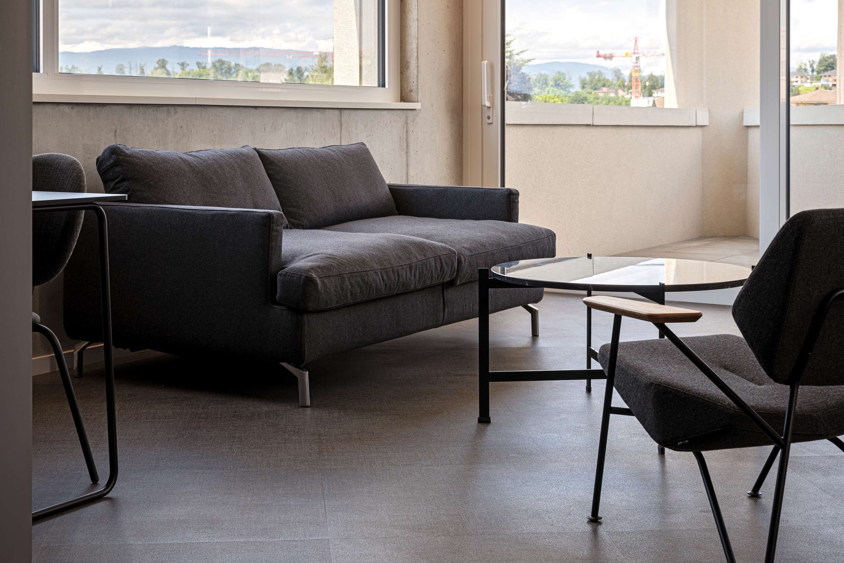 Una sala moderna con un sofá gris, una mesita y una silla.