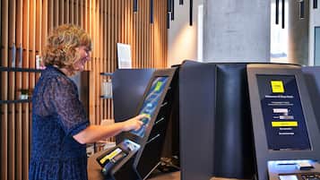 A woman interacting with a digital kiosk in a modern hotel setting.