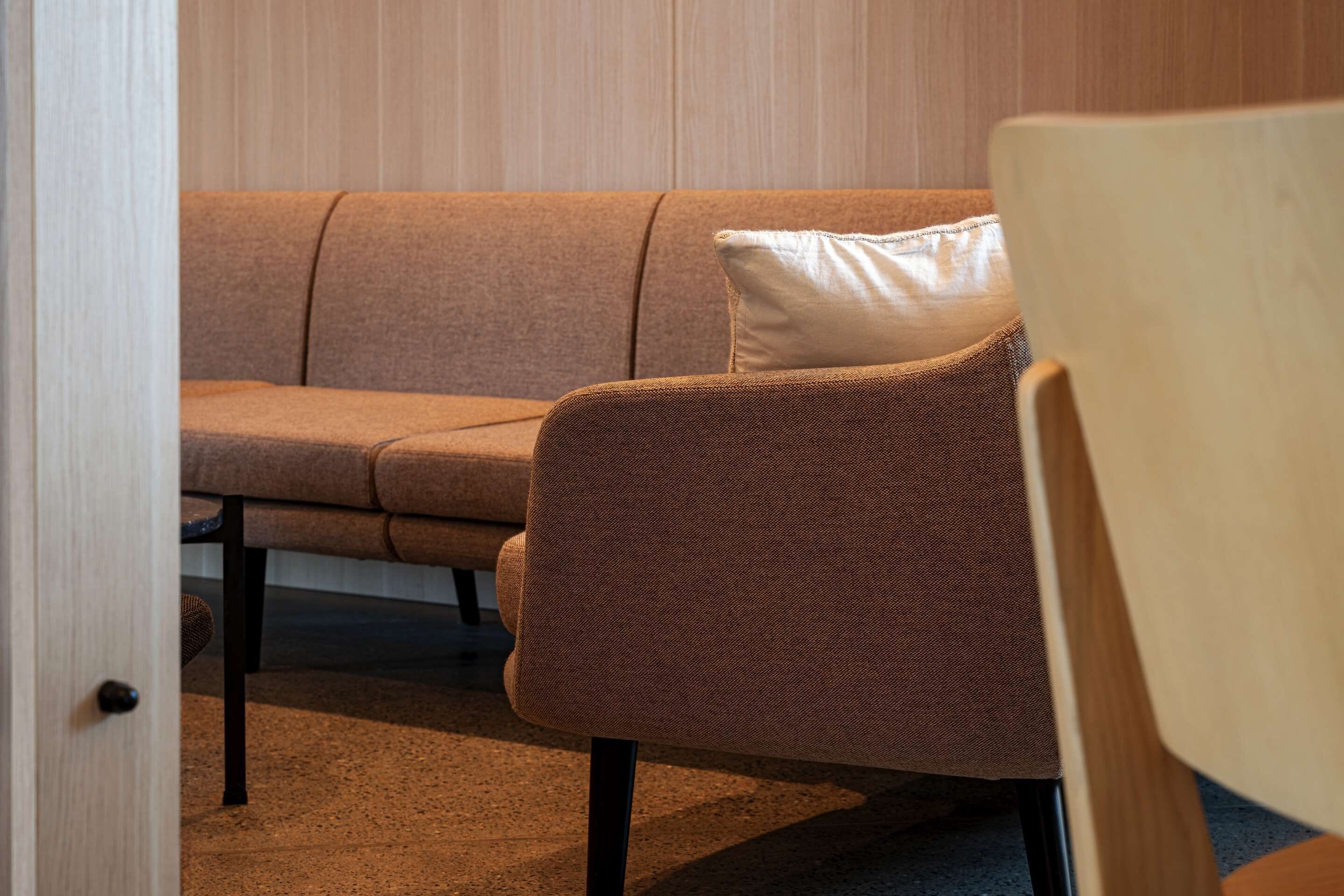 A modern living room with a brown sofa and a wooden chair.