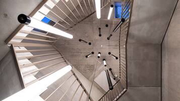 A spiral staircase with a concrete floor and metal railings, leading to an upper level.