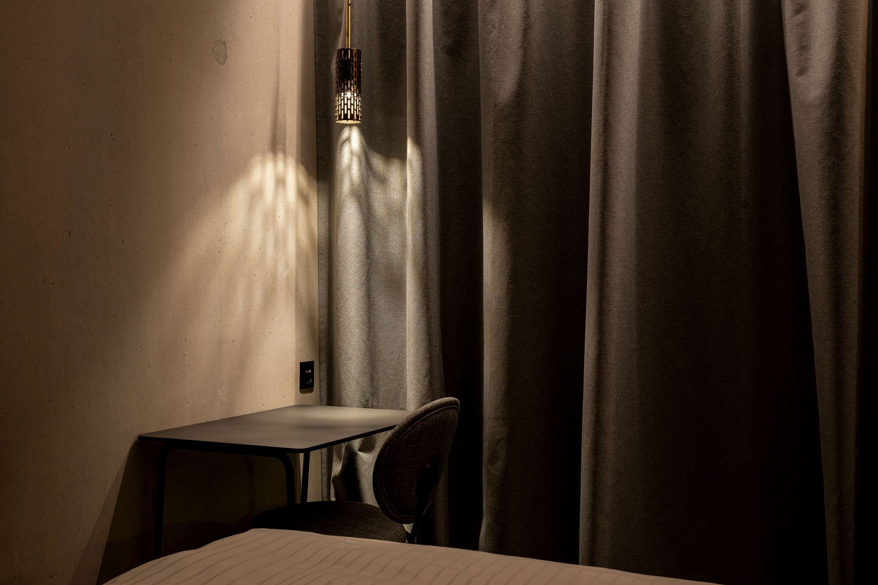 Ein Hotelzimmer mit einem Bett, einem kleinen Tisch, einem Stuhl und einer Pendelleuchte.