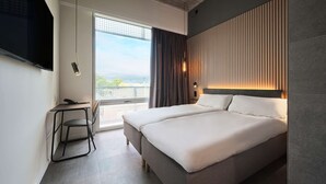 A modern hotel room with a large bed, a desk, and a TV. - Zleep Hotel Lausanne-Chavannes (Chavannes-près-Renens)