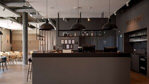 A modern bar area with a central counter, pendant lighting, and a 'WELCOME' sign on the wall. - Zleep Hotel Lausanne-Chavannes (Chavannes-près-Renens)