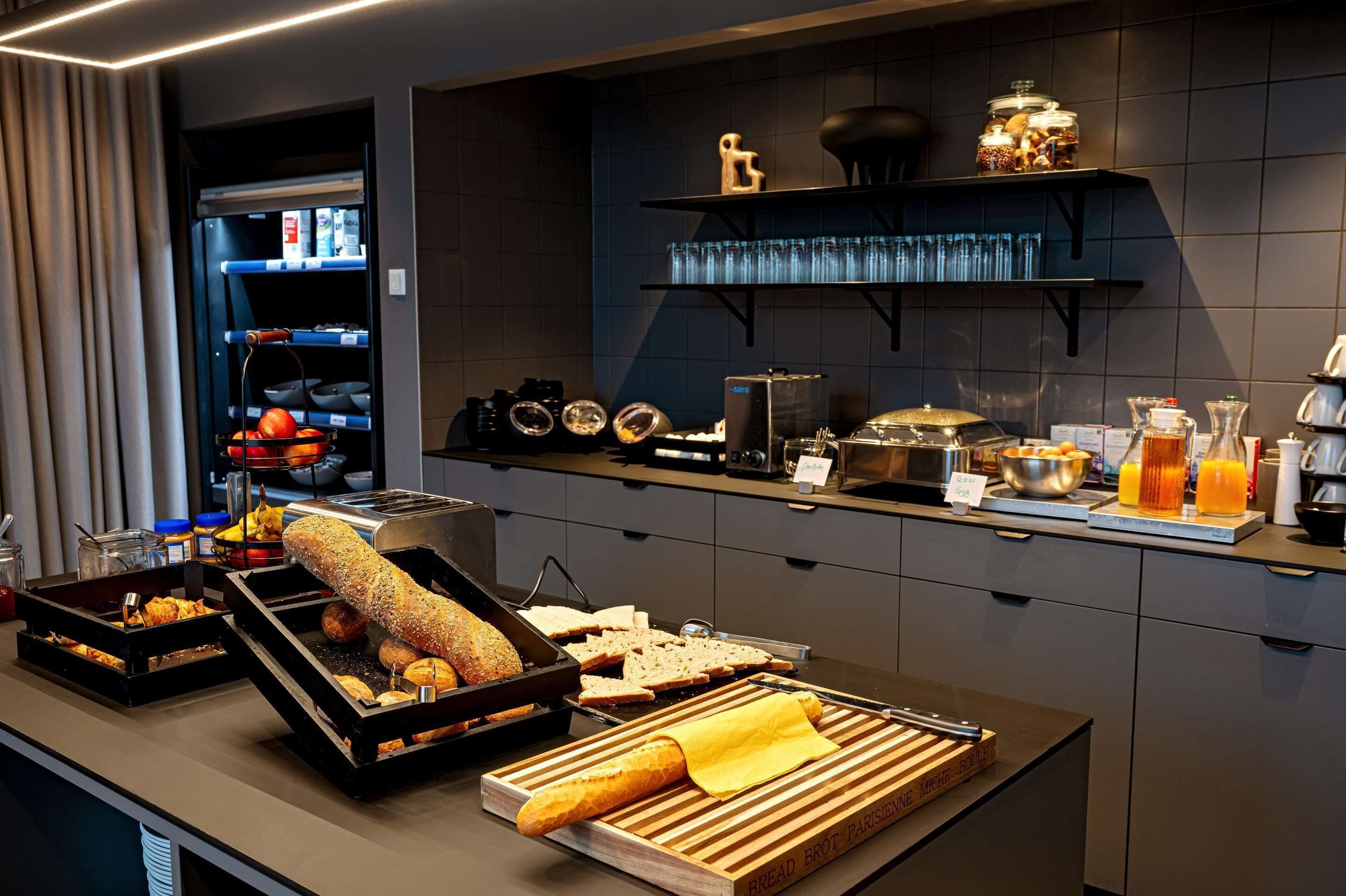 A breakfast buffet with bread, pastries, and beverages.