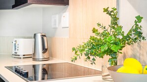 A modern kitchen with a built-in stove, a kettle, and a bowl of lemons. - Lagoon Beach 29A (Cape Town)