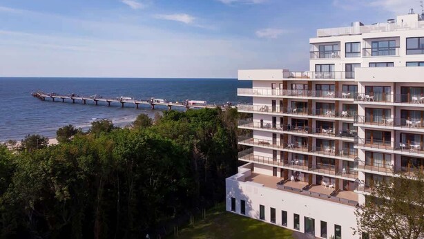 Un hotel moderno de varios pisos con balcones con vistas al mar.