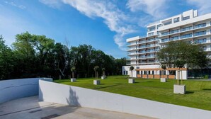 A modern building with multiple balconies and a well-maintained lawn area.