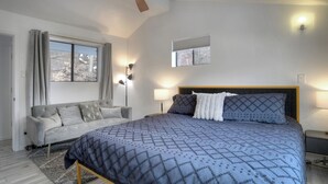 Un dormitorio con cama, sofá, lámpara de pie y luz empotrada en la pared.