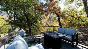 Terraza exterior con sofá, mesa y una chimenea.