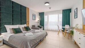 Una habitación de hotel moderna con una cama grande, un escritorio y un comedor.