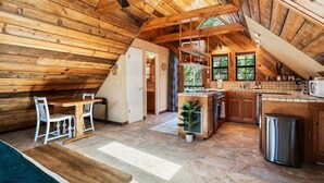Una cabaña de madera acogedora con cocina, comedor y una pequeña sala de estar.