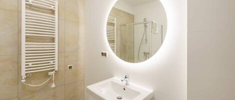 Een moderne badkamer met een ingebouwd toilet, een wastafel met spiegel en een douche.