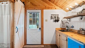 A compact kitchen with wooden cabinets, a blue refrigerator, and a window with a view.