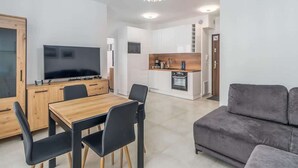 A modern living room with a wooden dining table, black chairs, and a grey sofa.