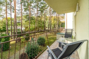 Ein Balkon mit Metallgeländer, einem Glastisch und zwei Stühlen.
