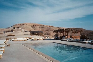 Una piscina al aire libre, sombrillas, tumbonas