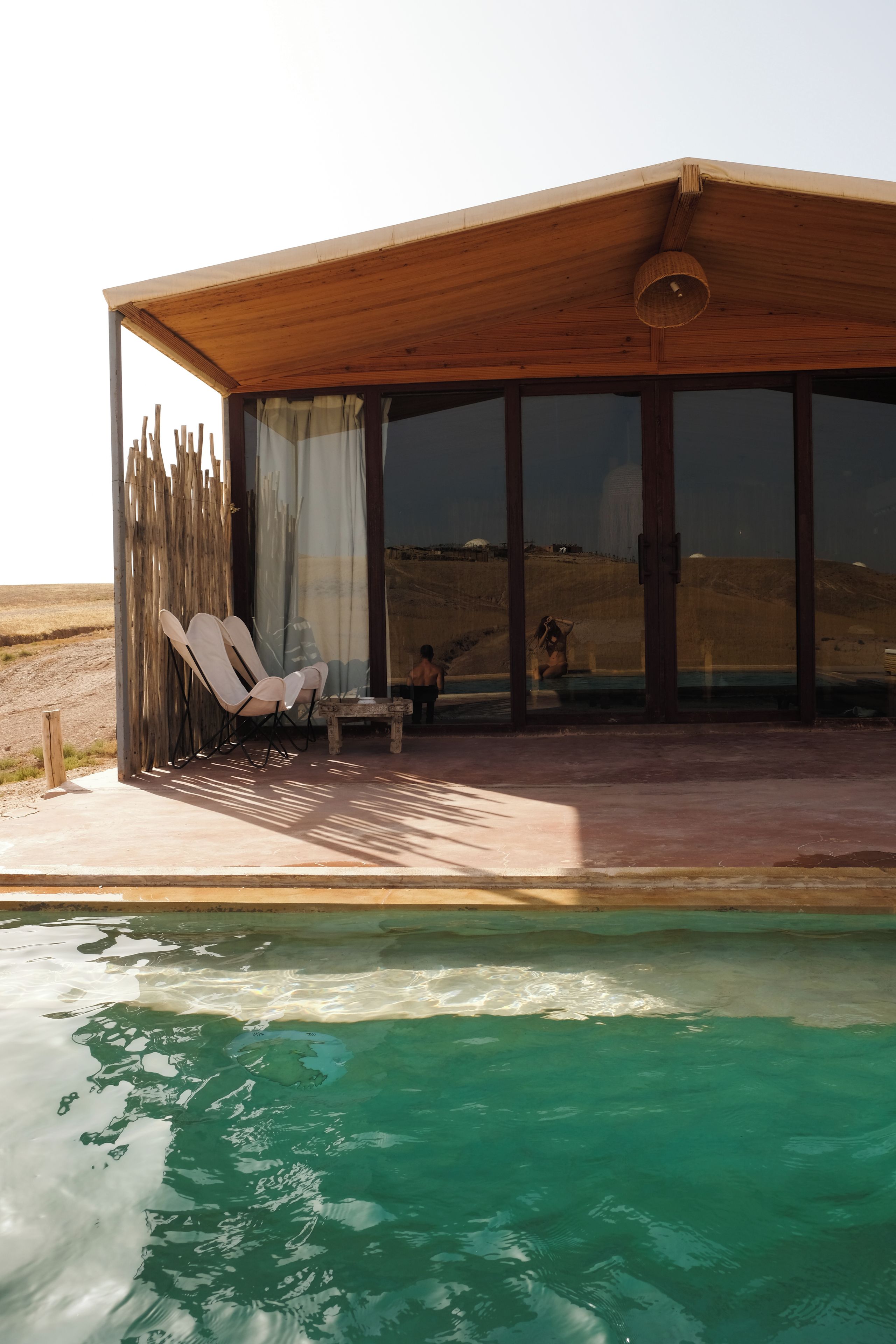 Un área junto a la piscina con una zona de estar cubierta, una piscina y vistas al paisaje.