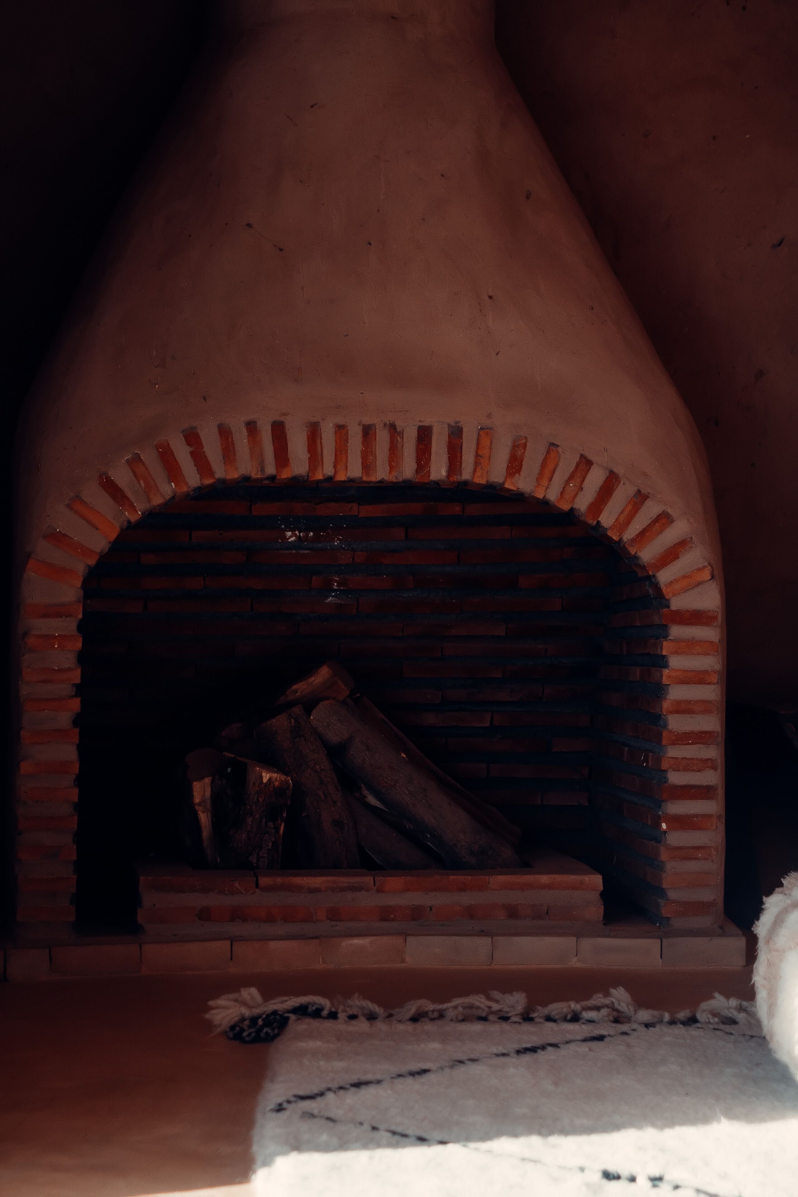 A brick fireplace with a rustic design, a fire log, and a white rug on the floor.