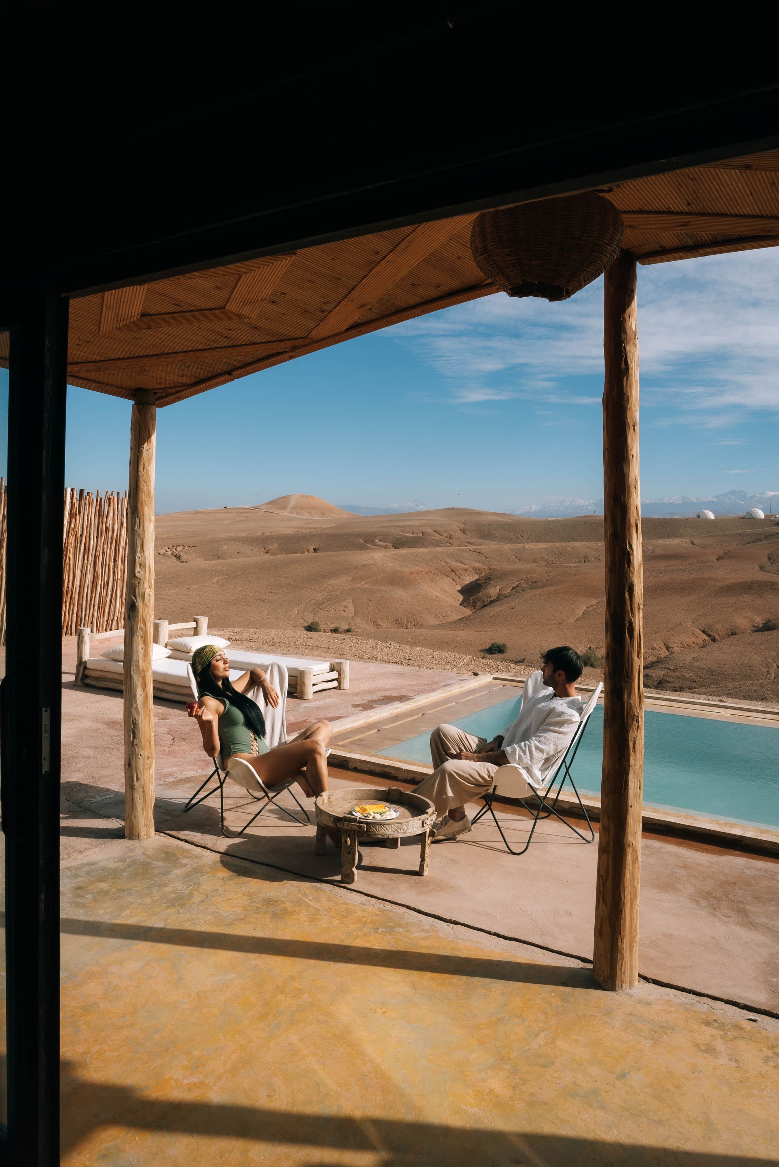 A poolside area with lounge chairs and a view of a desert landscape.