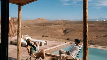 A poolside area with lounge chairs and a view of a desert landscape.