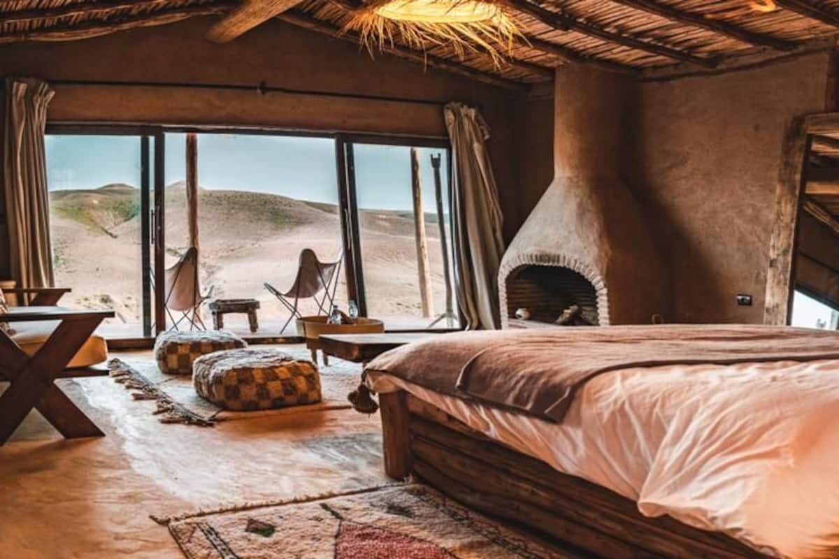 Une pièce chaleureuse avec un grand lit, une cheminée rustique et une vue sur le désert.