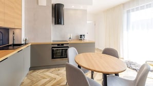 Una cocina moderna con una isla central, horno empotrado y un amplio ventanal con cortinas.