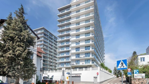 Un edificio moderno de varios pisos con fachada blanca y balcones.