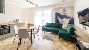 Una sala moderna con un sofá verde, una mesa de comedor con sillas y una zona de cocina.