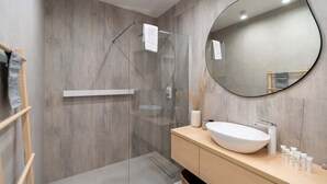 Une salle de bain moderne avec un mur en bois, un miroir rond, un lavabo blanc et un porte-serviettes.