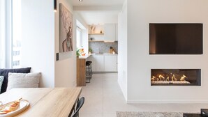 Une cuisine moderne dotée d’un îlot central, d’un coin repas avec une table en bois et d’une cheminée.