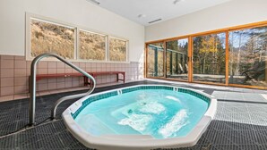 A hot tub with a view of trees and a bench.