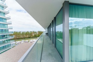 Un bâtiment moderne doté d’un balcon en verre donnant sur un espace paysager aménagé.