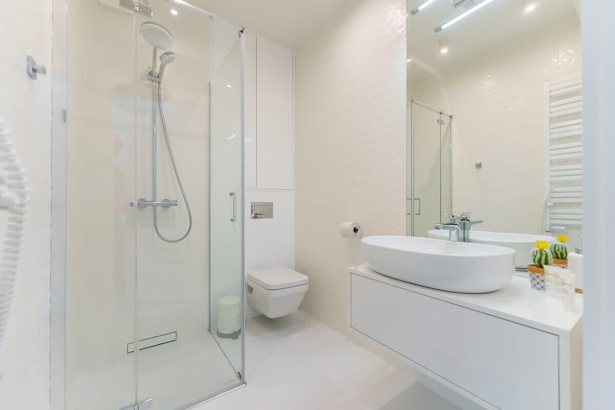 A modern bathroom with a glass-enclosed shower, a white sink, and a toilet.