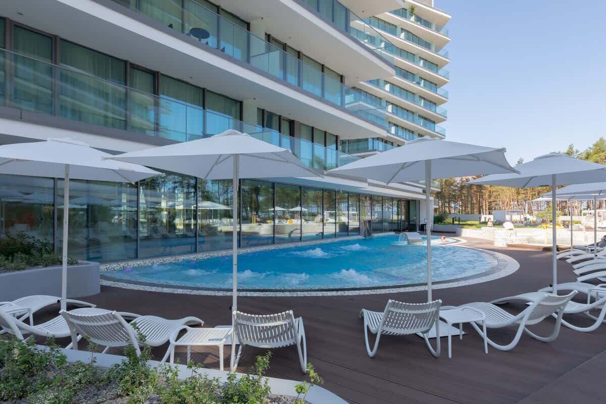 A modern hotel with a rooftop pool area, sun loungers, and umbrellas.