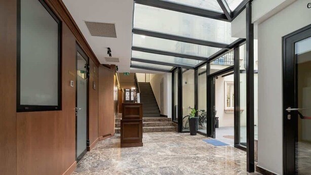 En hotelllobby med ett marmorgolv, träpanel, en trappa och glasdörrar som leder till andra delar av hotellet.