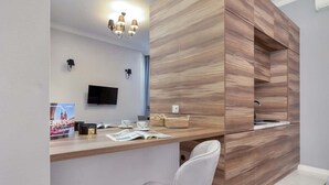 Ett modernt receptionsområde med en väggpanel i trä, en platt-TV och en sittgrupp med en vit stol.