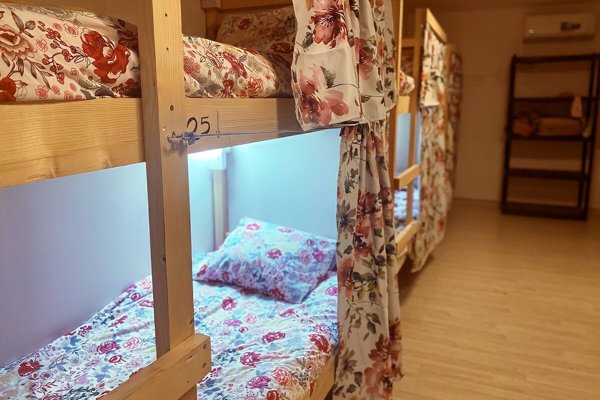 A row of bunk beds with floral-patterned bedding and a wooden floor.