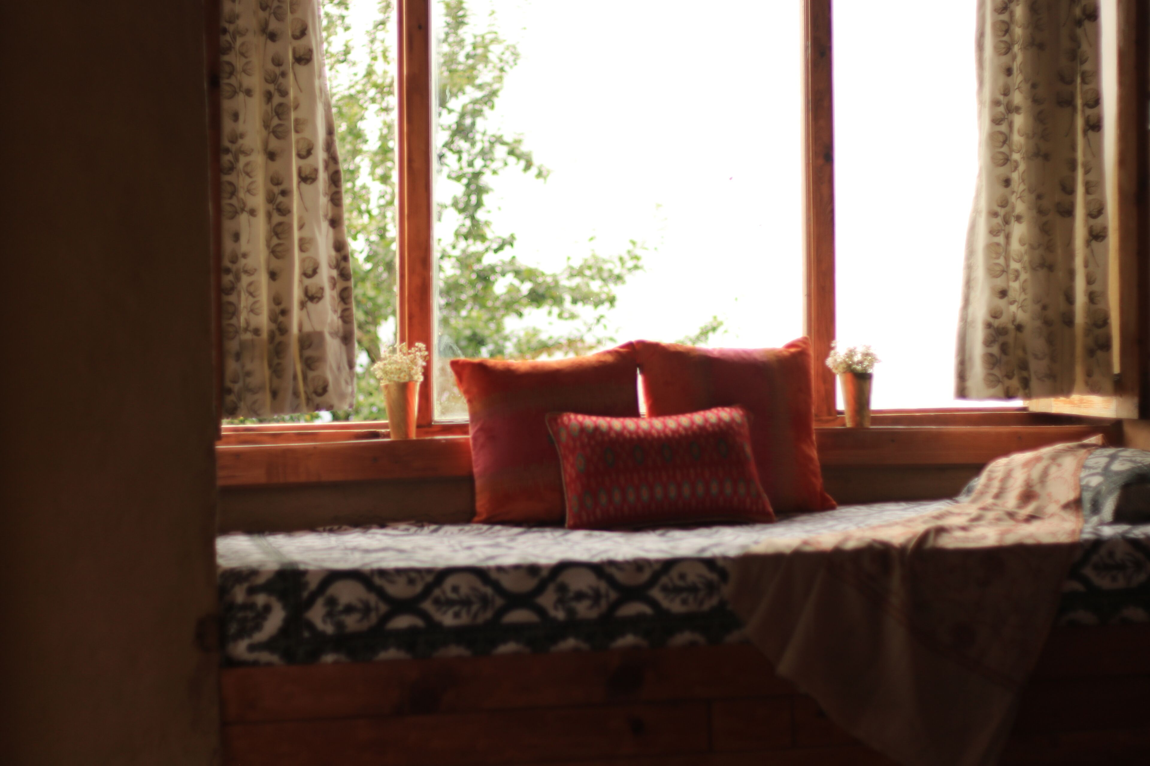 A bedroom with a bed, pillows, and a window with curtains.