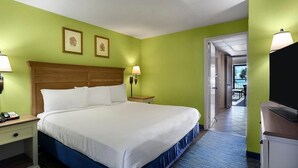 A hotel room with a large bed, two bedside lamps, a nightstand with a phone, and a TV on a stand.