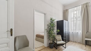 A modern room with a wooden floor, a potted plant, a sofa, a chair, and a wardrobe. - Stylish Apartments near AKH (Vienna)