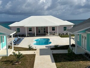 A house with a swimming pool, a covered patio, and a view of the ocean.