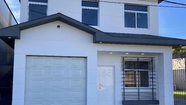 A two-story house with a white exterior, a garage, and a front door. - Casa Relax 3 (Paysandú)