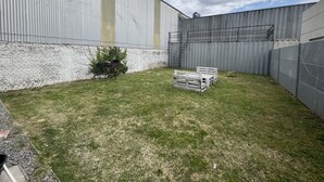 A grassy outdoor area with a brick wall, a metal fence, and a staircase leading to a higher level. - Casa Relax 3 (Paysandú)