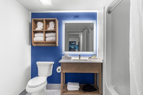 A bathroom with a white toilet, a wooden vanity with a mirror, and a blue accent wall.
