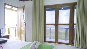 Una habitación de hotel con cama, balcón y vistas, además de cortinas.