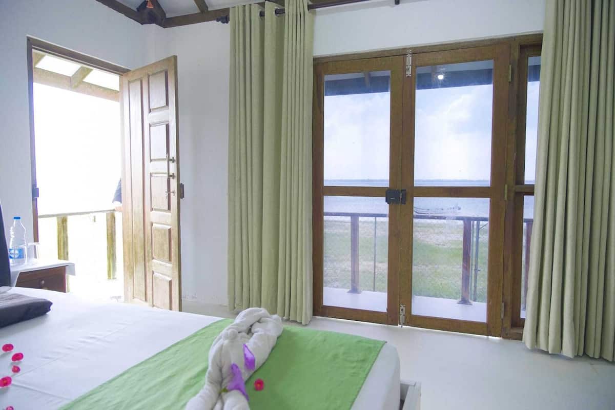 A hotel room with a bed, a balcony with a view, and curtains.
